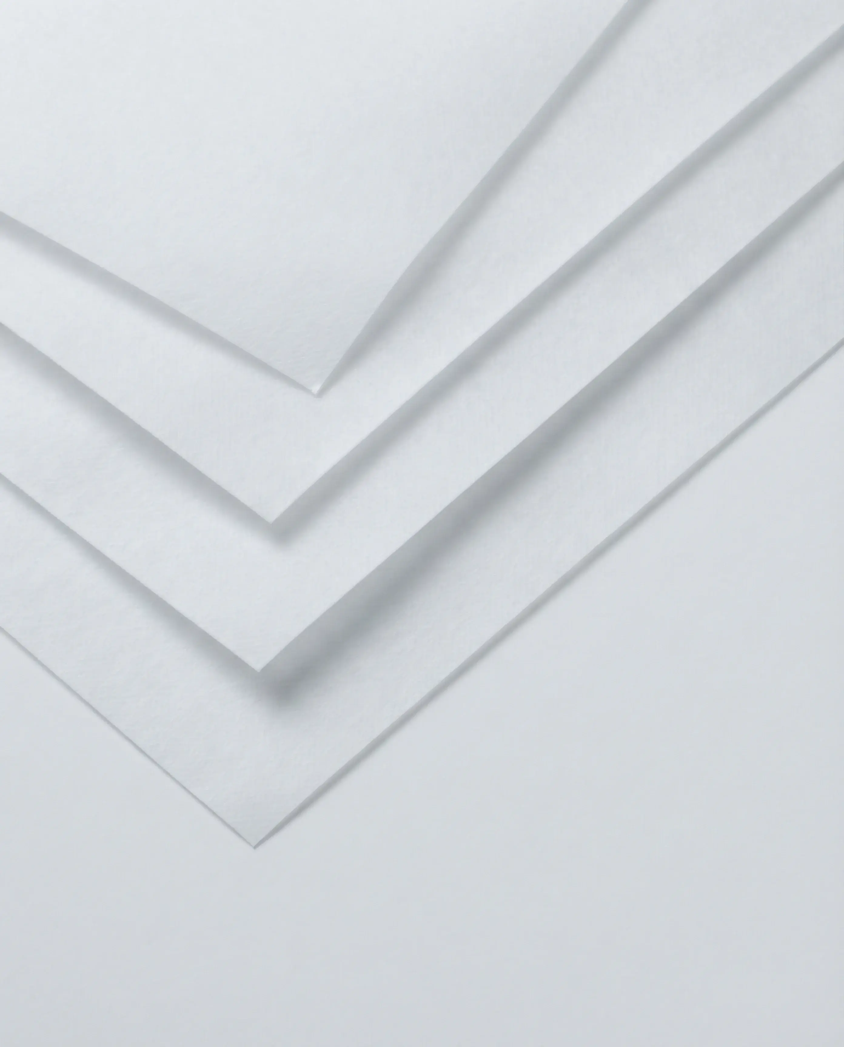 Four sheets of white medical-grade non-woven fabric fanned out in overlapping layers, showing the fibrous surface and clean-cut edges