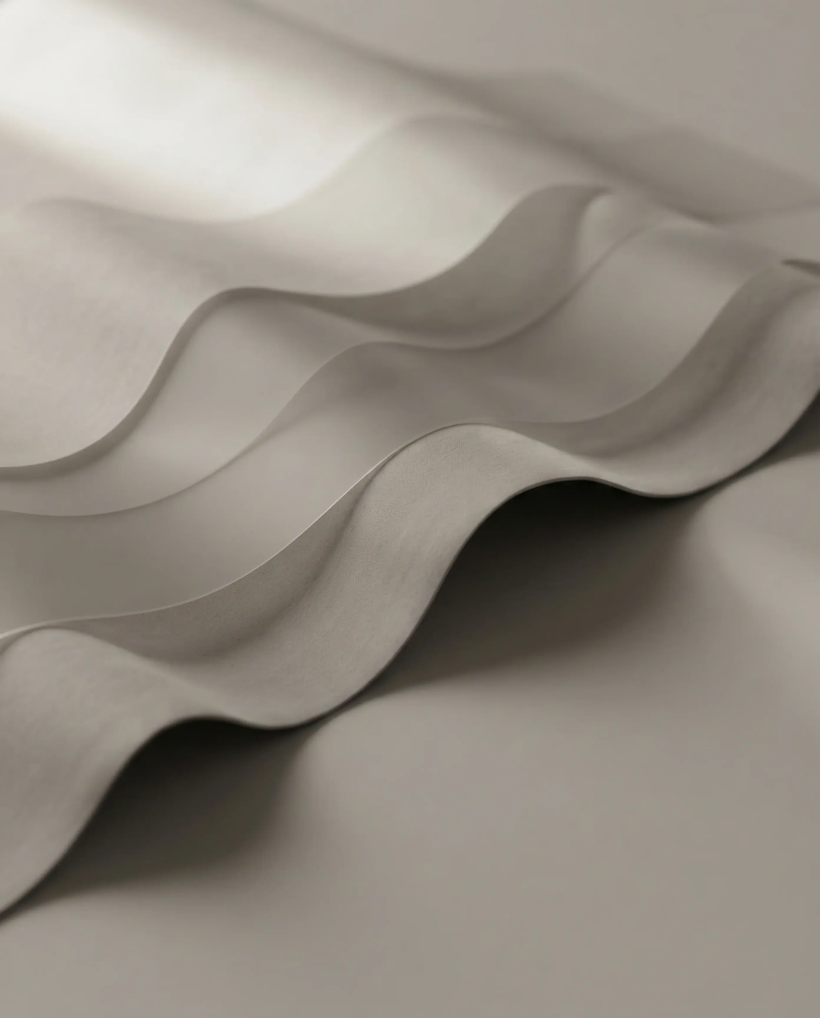 A sheet of soft grey non-woven fabric draped into deep, even waves under raking light